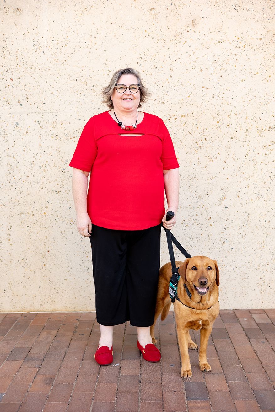 Photo of an individual smiling at the camera with their service dog.