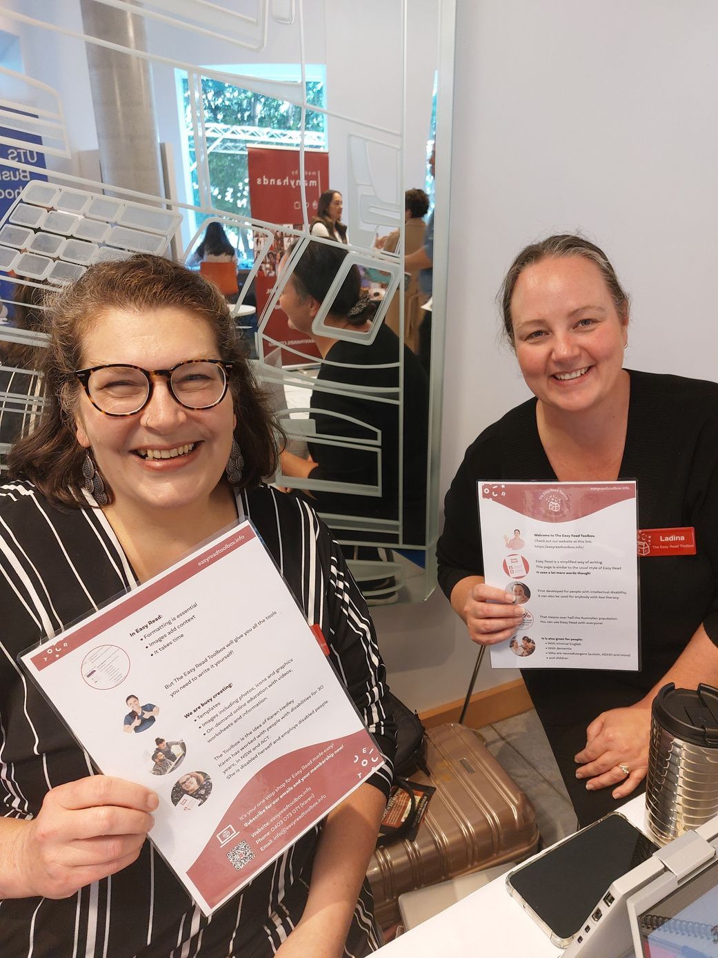 A photo of a founder Karen on the left and our General Manager Ladina
Castle on the right, both smiling at the camera holding a paper copy of an exampleof Easy Read document, while at convention.