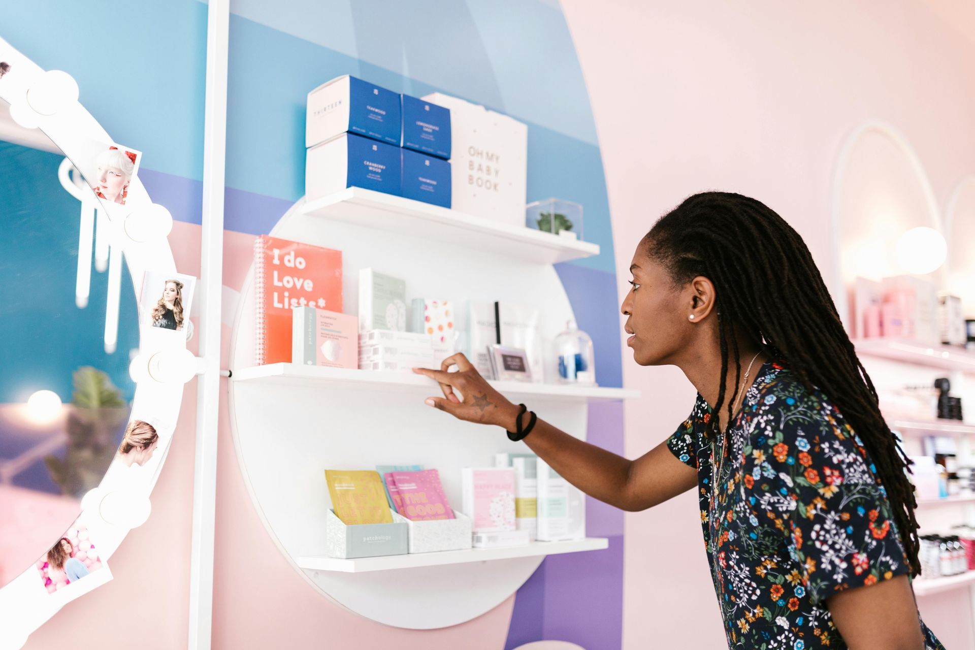 Woman browses shelves in a brightly-colored retail store, reaching for a product.