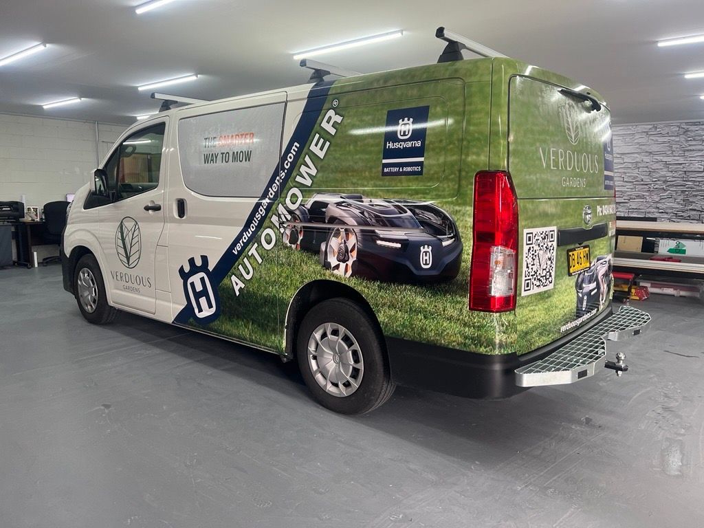 A White Van With a Green Wrap on it is Parked in a Garage — Metric CNC In Morisset, NSW