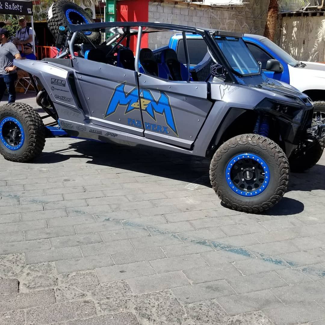 Silver off-road buggy with blue accents and large tires parked on a paved street