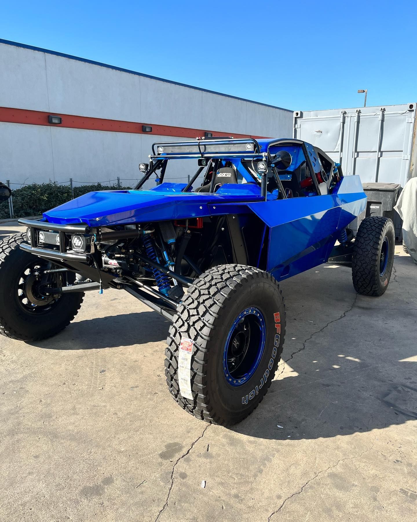 Blue off-road buggy with oversized tires parked outdoors in a lot