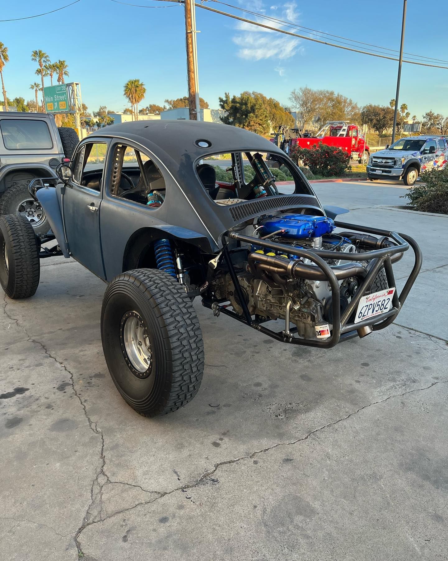 Black off-road dune buggy with exposed engine and oversized tires parked on a street.