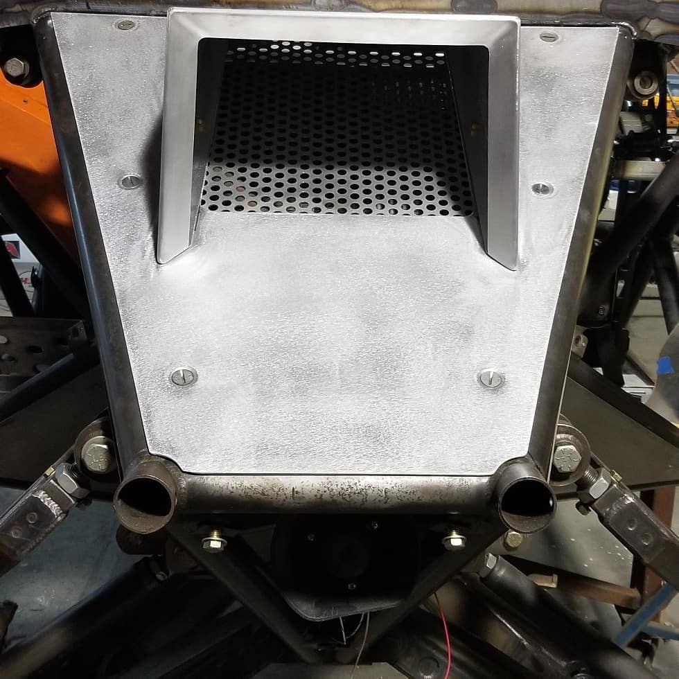 Metal robot front panel with a perforated grille and two cylindrical mounts, surrounded by mechanical components.