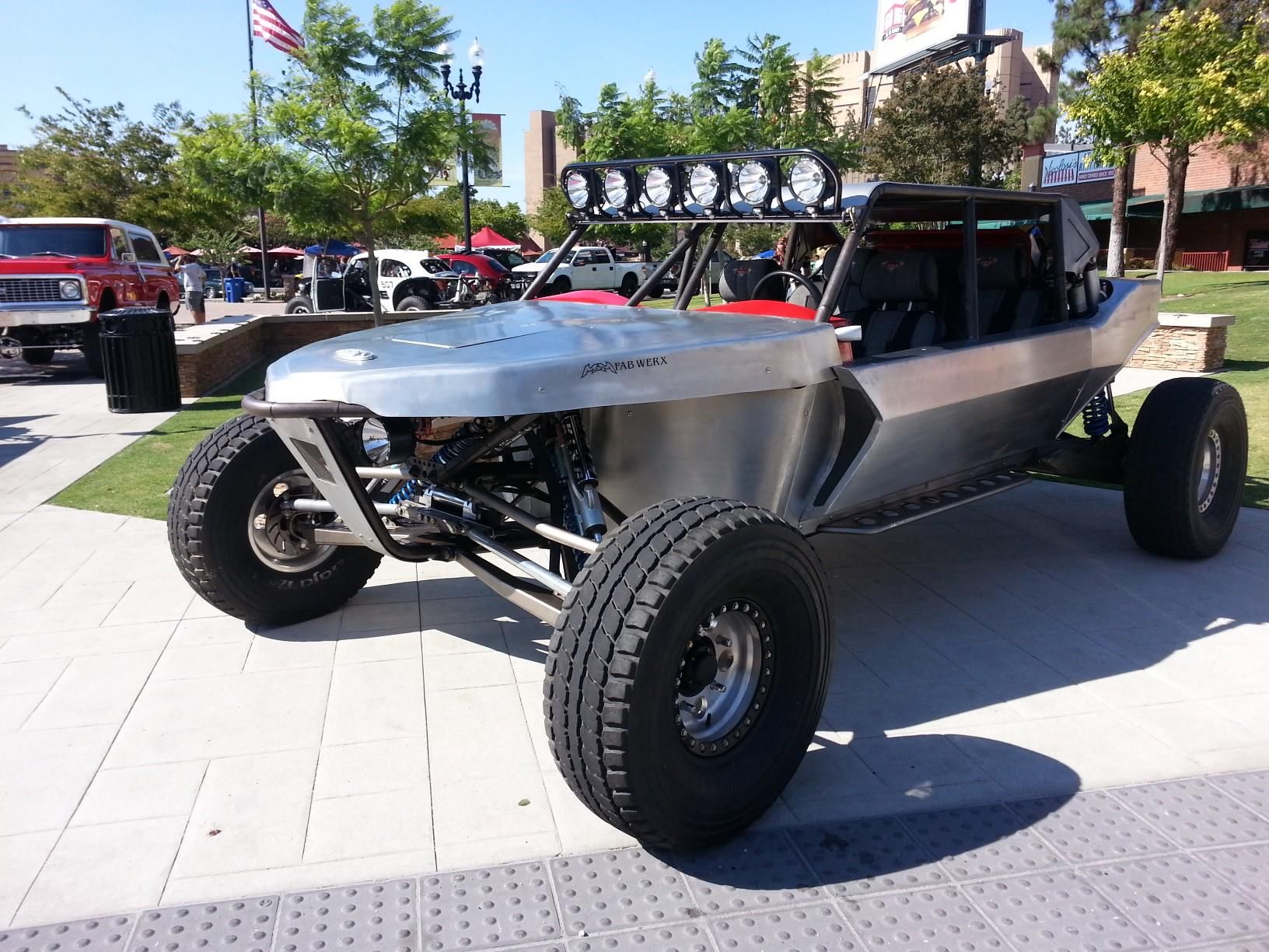 Custom off-road dune buggy with roll cage and large tires parked outdoors in sunlight
