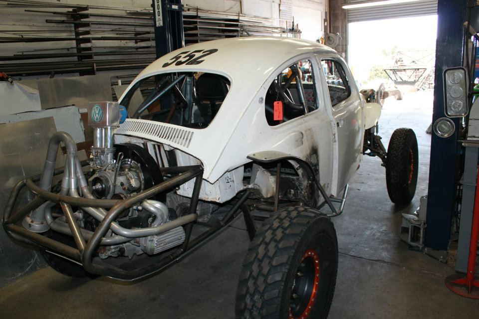 White off-road buggy in a garage with exposed front engine and large tires