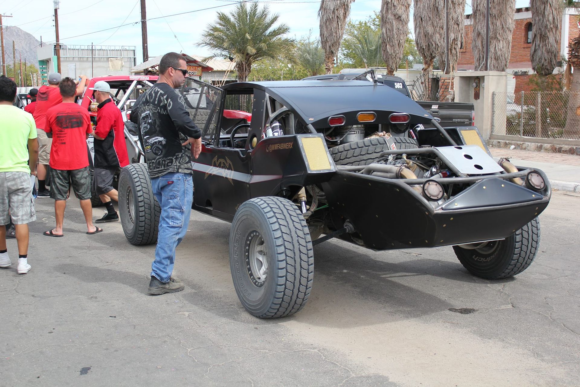 Black off-road buggy on a street with people gathered around it