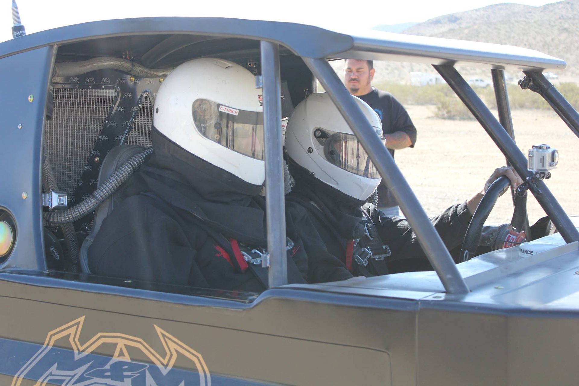 Person in a race car wearing a white helmet, seated inside the blue cockpit.