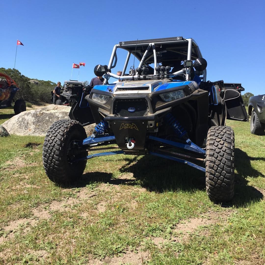 Blue and black off-road side-by-side UTV parked on grass in a sunny outdoor field