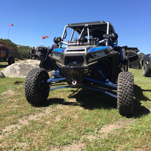 Blue off-road buggy with oversized tires on a grassy trail under a clear sky