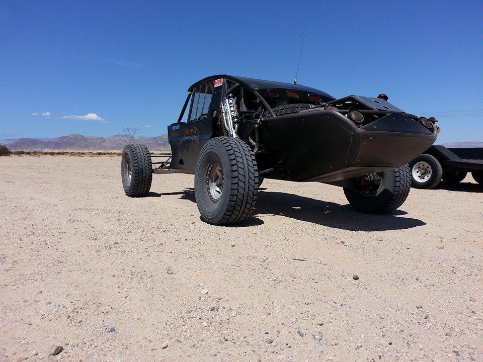 Black off-road buggy parked on a desert plain under a clear blue sky