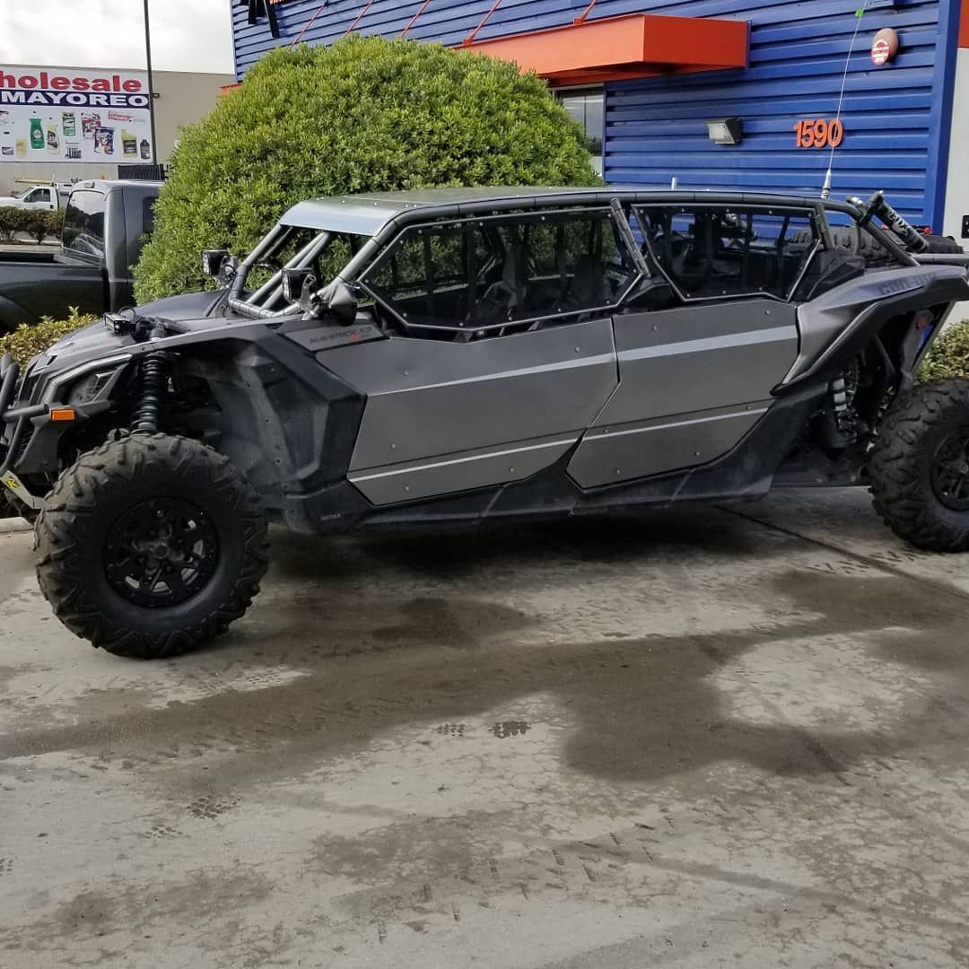 Black off-road side-by-side buggy parked outside a blue building with orange awning and wet pavement.