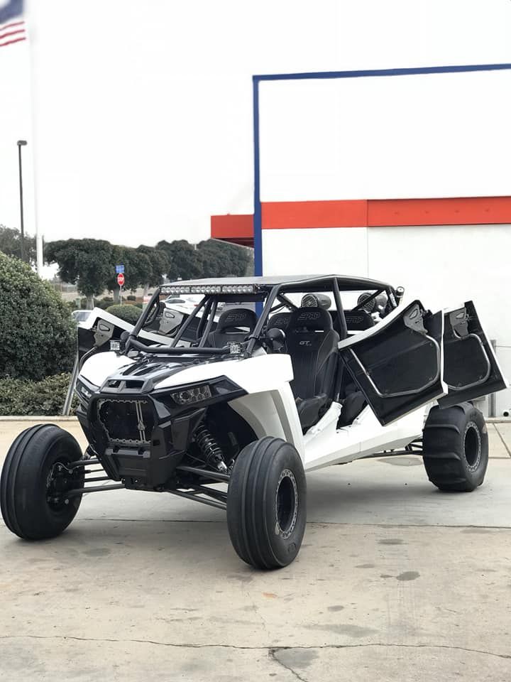 White open-frame off-road buggy with exposed roll cage parked outdoors on pavement