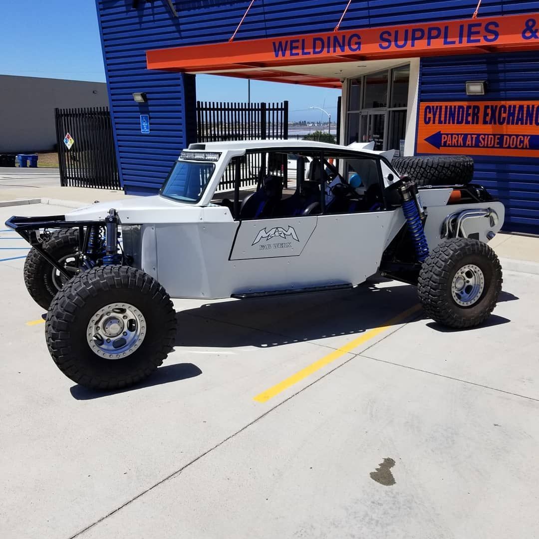 White off-road buggy parked outside a blue welding supply shop on a sunny day