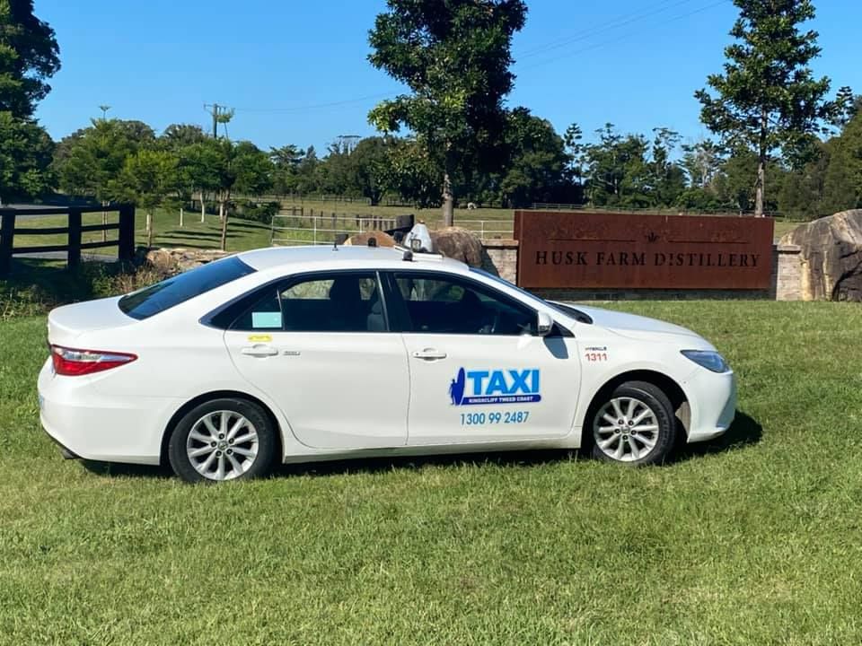 A Row Of White Taxis Are Parked On The Side Of The Road — Kingscliff Tweed Coast Taxis Pty Ltd In Kingscliff, NSW