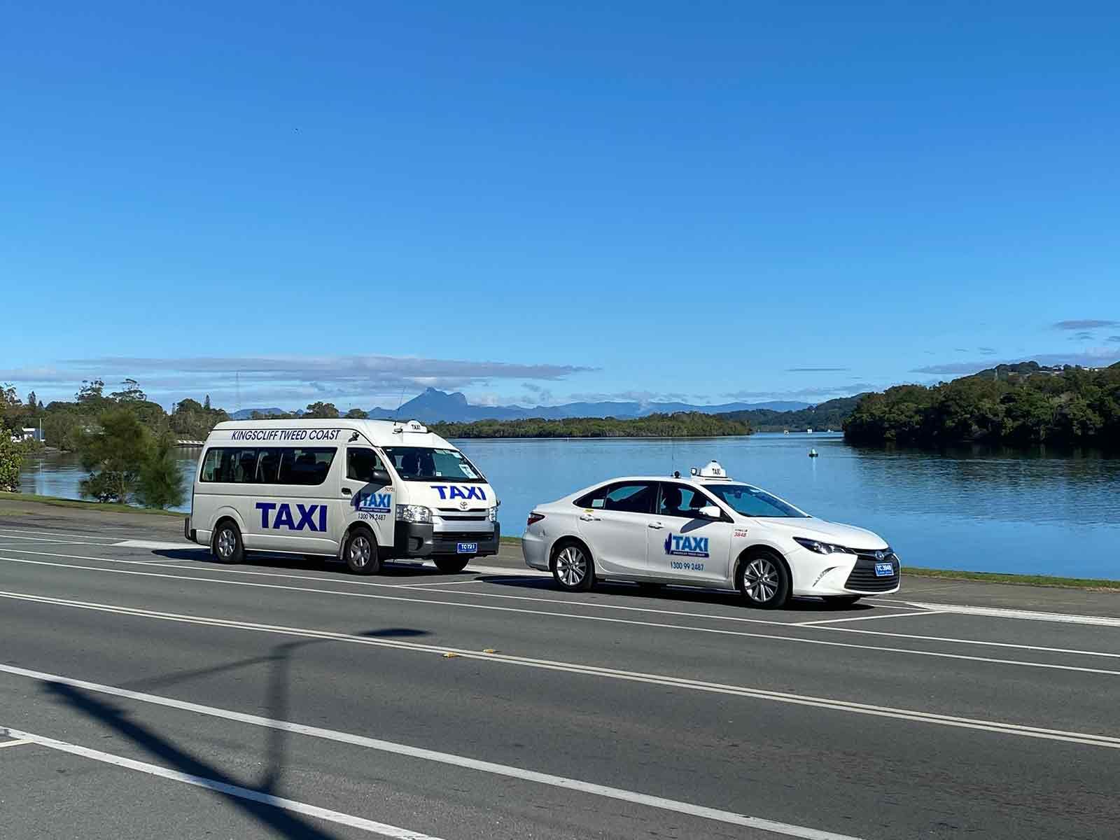 Two Taxis Are Driving Down A Highway Next To A Body Of Water — Kingscliff Tweed Coast Taxis Pty Ltd In Kingscliff, NSW