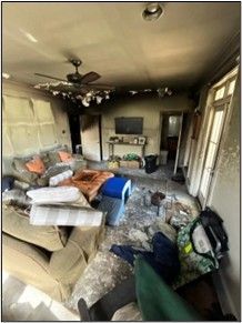 Interior of a room severely damaged by fire; soot-covered ceiling, charred walls, and debris scattered everywhere.