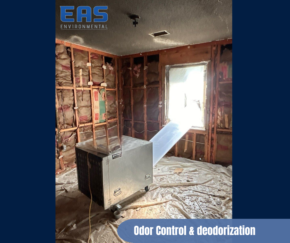 Workers painting a room with drop cloths. One on cart with pole, other on table in room with exposed ceiling.