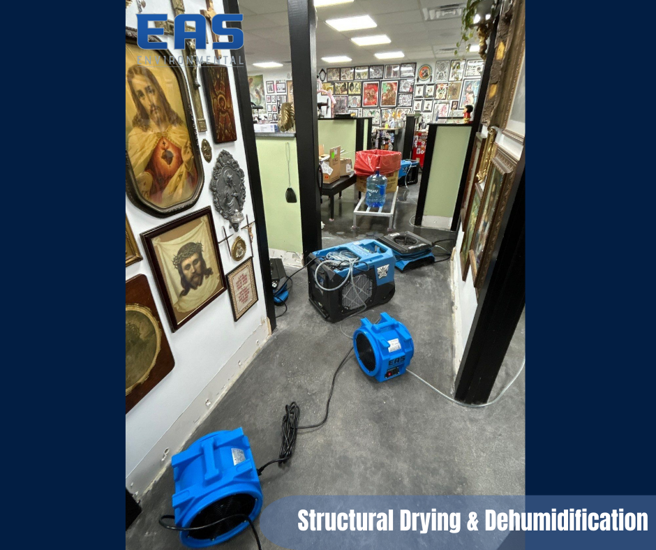 Workers painting a room with drop cloths. One on cart with pole, other on table in room with exposed ceiling.