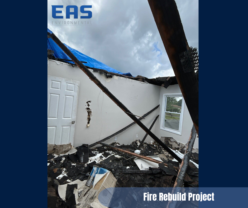 Workers painting a room with drop cloths. One on cart with pole, other on table in room with exposed ceiling.