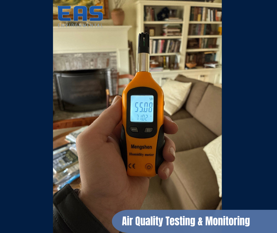 Workers in safety gear on a roof removing material with abatement equipment; urban setting with buildings in background.