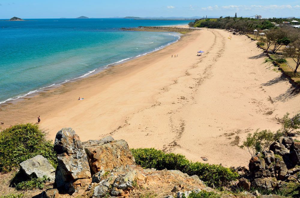 An Aerial View of A Sandy Beach Next to A Body of Water — NQ Plaques & Trophies In Mackay, QLD