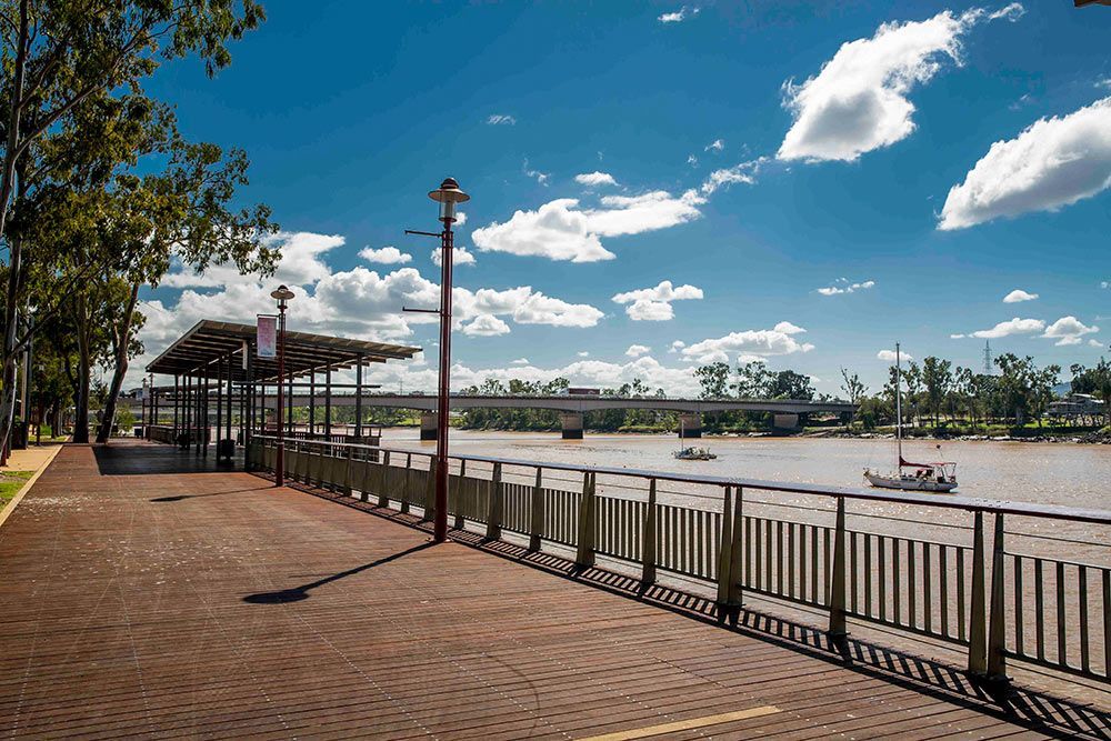 A Brick Walkway Leading to A River with A Bridge in The Background — NQ Plaques & Trophies In Rockhampton, QLD