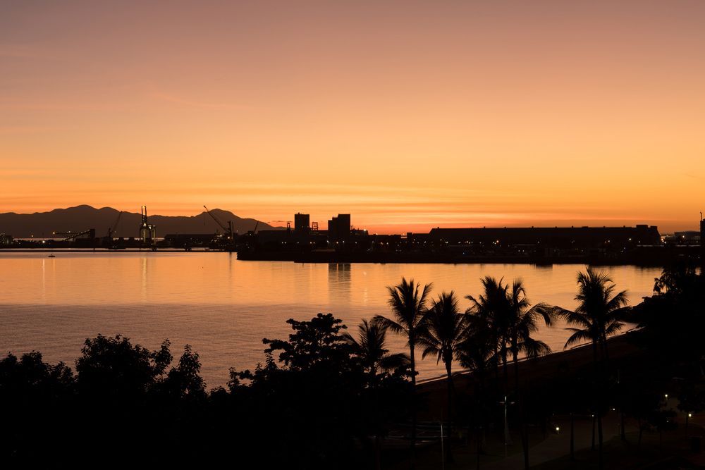A Sunset Over a Body of Water with Palm Trees in The Foreground — NQ Plaques & Trophies In Townsville, QLD