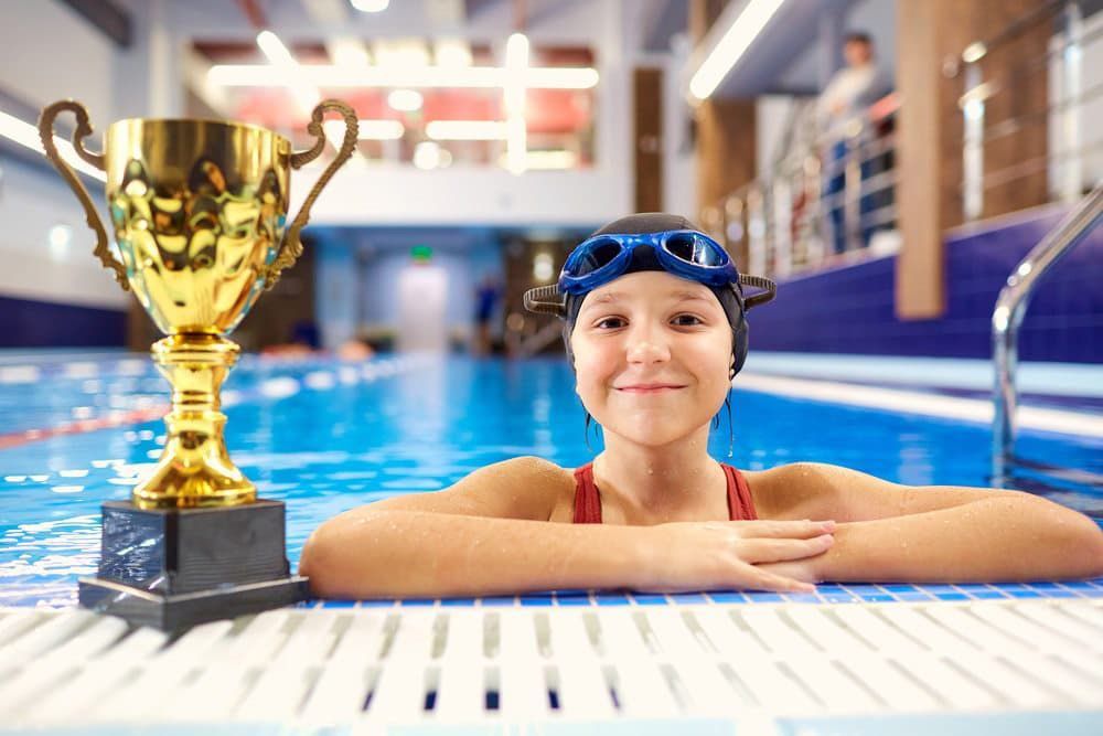Girl Child In Pool With Champion Trophy — NQ Plaques & Trophies In Kirwan, QLD