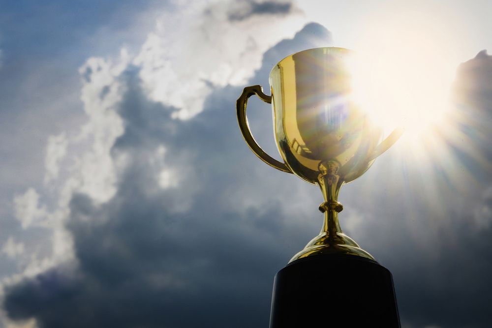 A Golden Trophy Is Standing In Front Of A Cloudy Sky — NQ Plaques & Trophies In Rockhampton, QLD