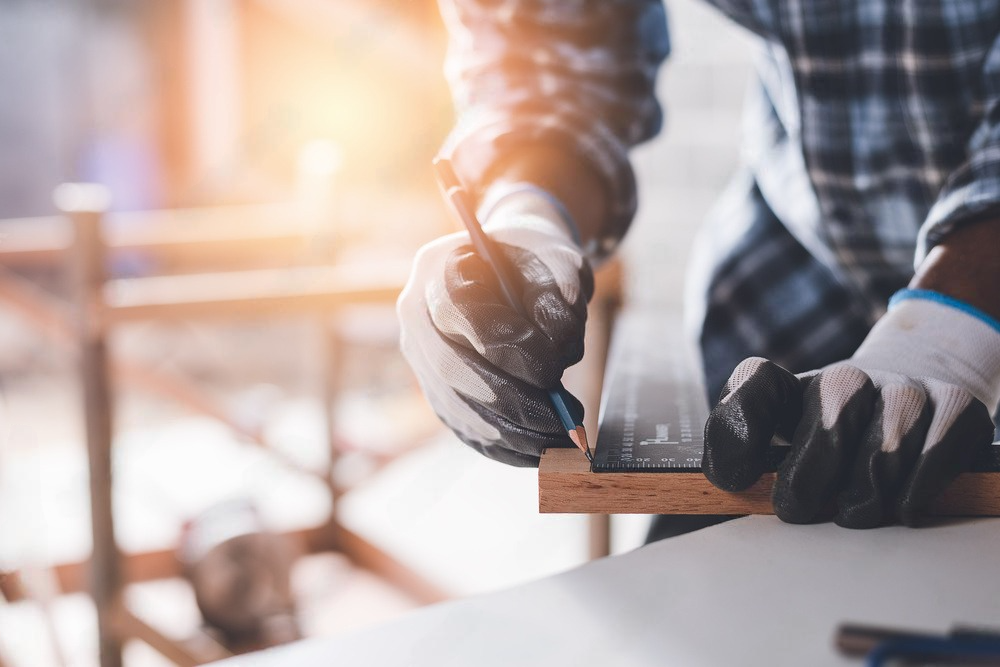 a man is cutting a piece of wood with a hammer .