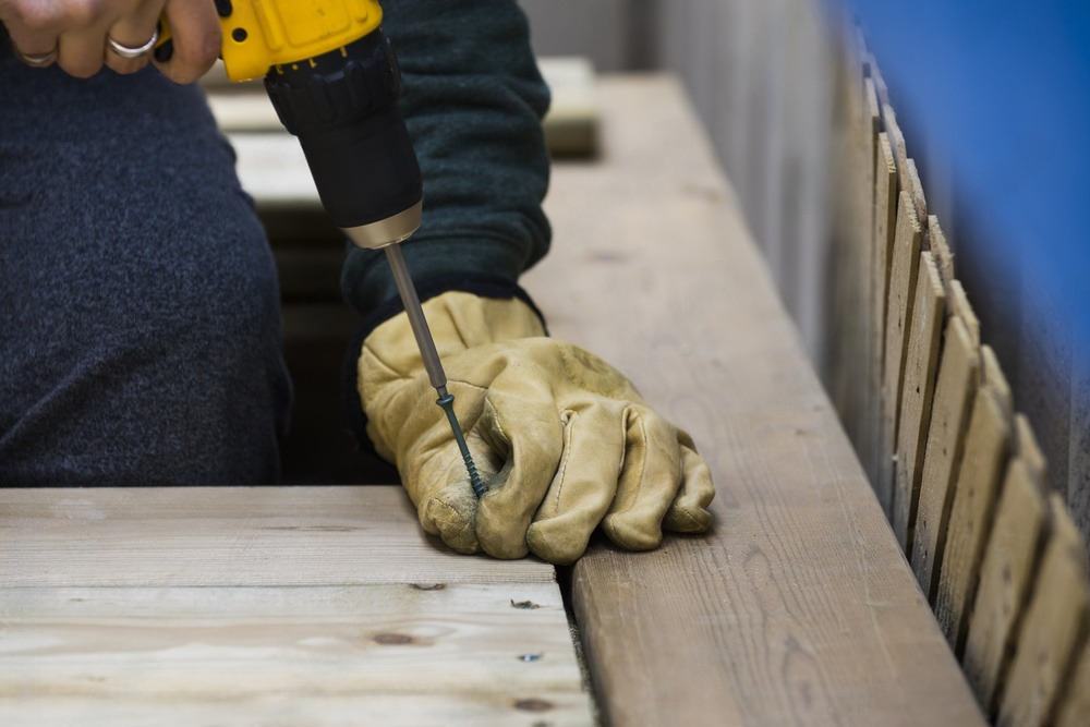 a person is using a drill on a piece of wood .