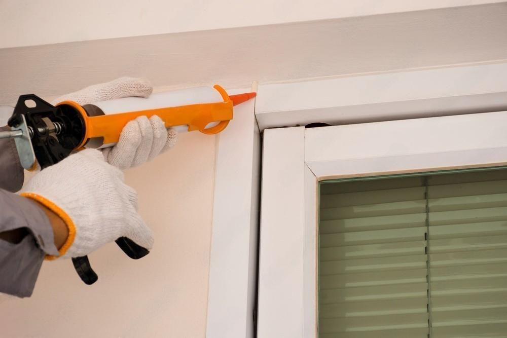 a person is applying sealant to a window frame .