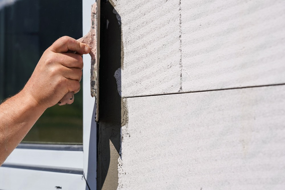 a man is plastering a window with a spatula .