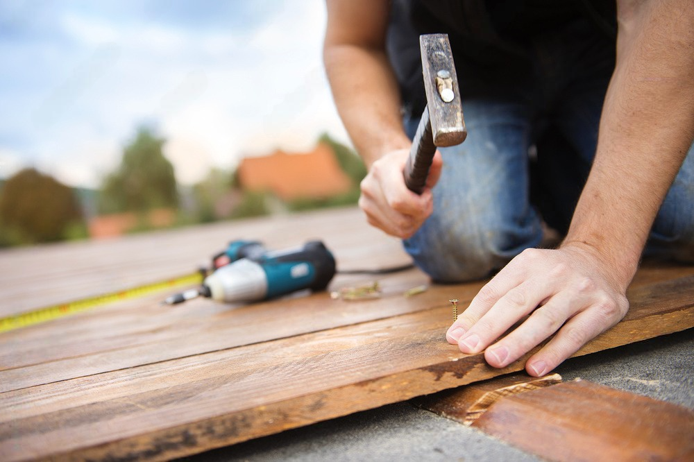 a man is using a hammer to hammer a piece of wood .