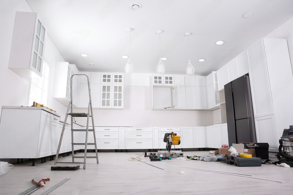 a kitchen is being remodeled with white cabinets and black appliances .