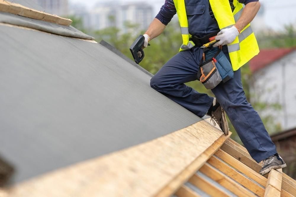 a man in a yellow vest is working on a roof .