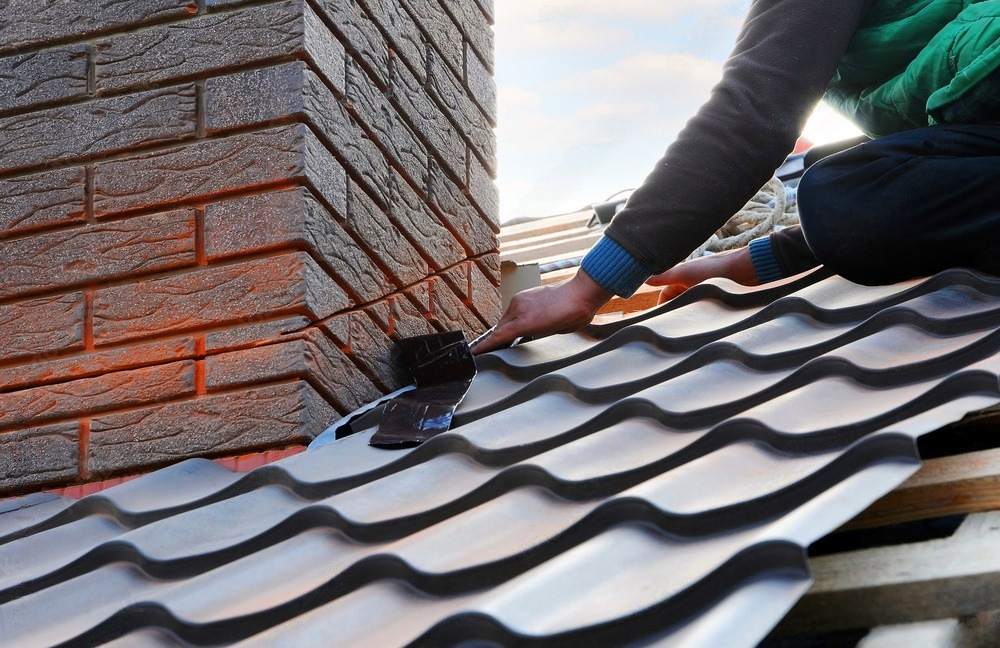 a man is working on a roof with a brick chimney in the background .