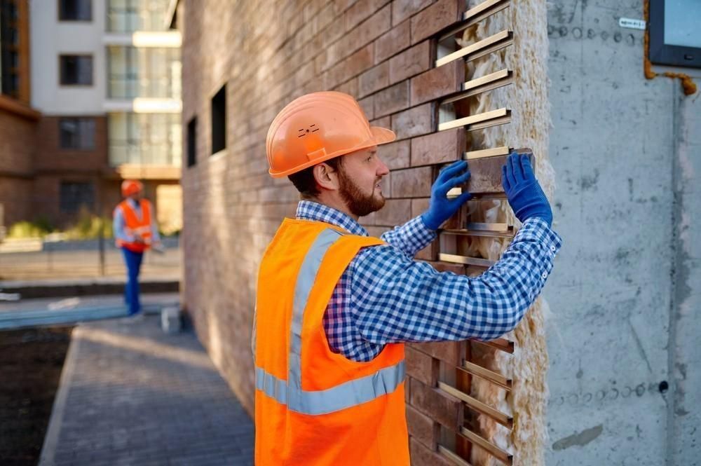 a construction worker is working on a brick wall .