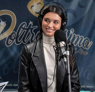 Una donna che indossa delle cuffie e una giacca di pelle è in piedi davanti a un microfono.