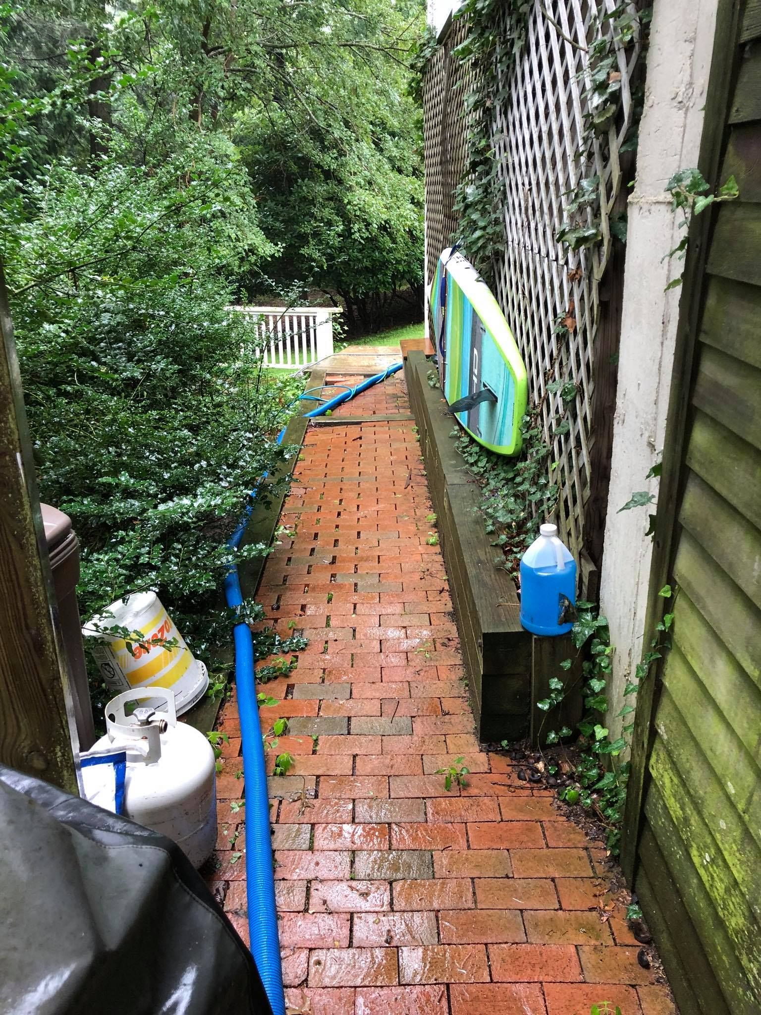 A brick walkway with a surfboard on the side of it.