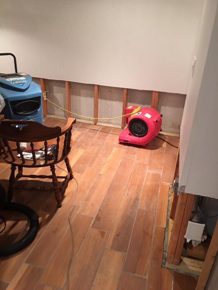 A room with a wooden floor , a chair , and a red air conditioner.