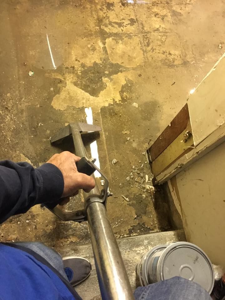 A person is sitting on a staircase holding a metal railing.