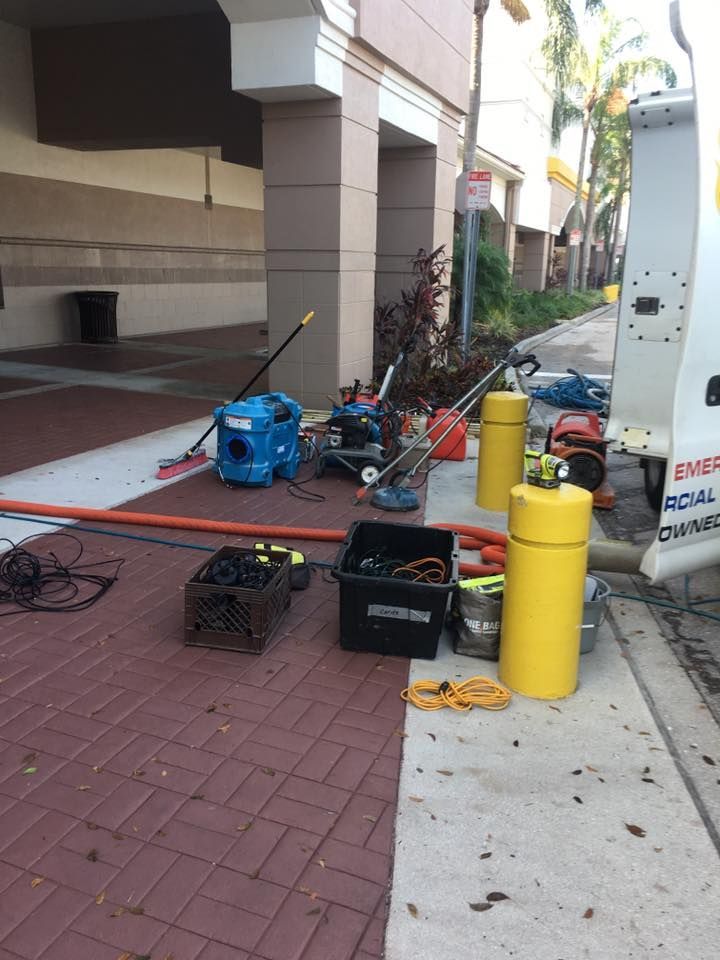 A white van is parked on a sidewalk next to a building.