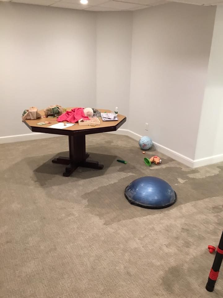 There is a table in the middle of the room with toys on the floor.