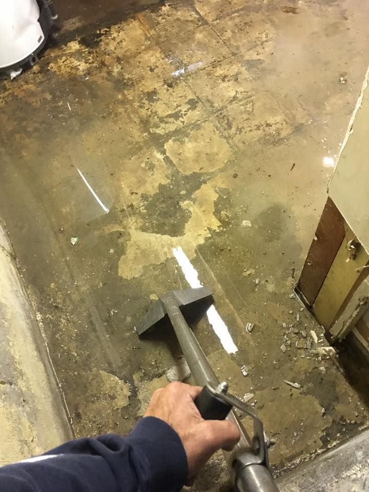 A person is cleaning a dirty floor with a vacuum cleaner.