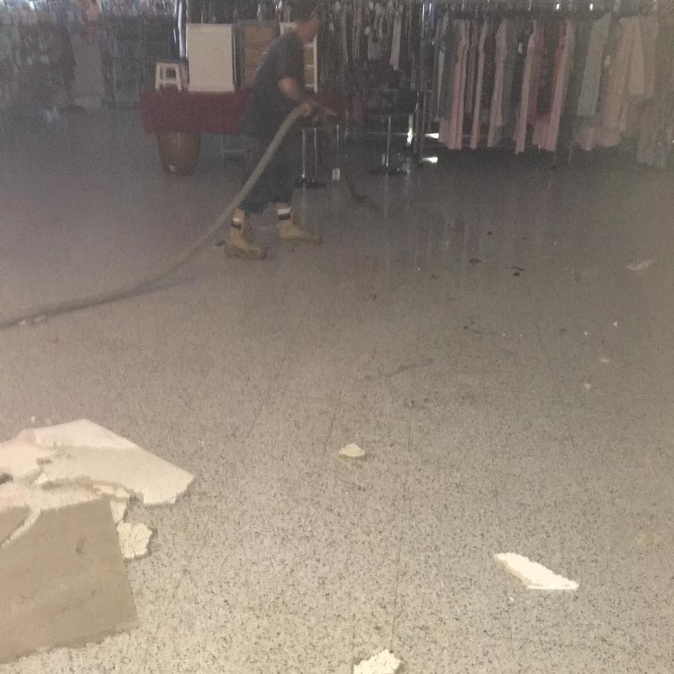 A man is using a vacuum cleaner to clean the floor of a store.
