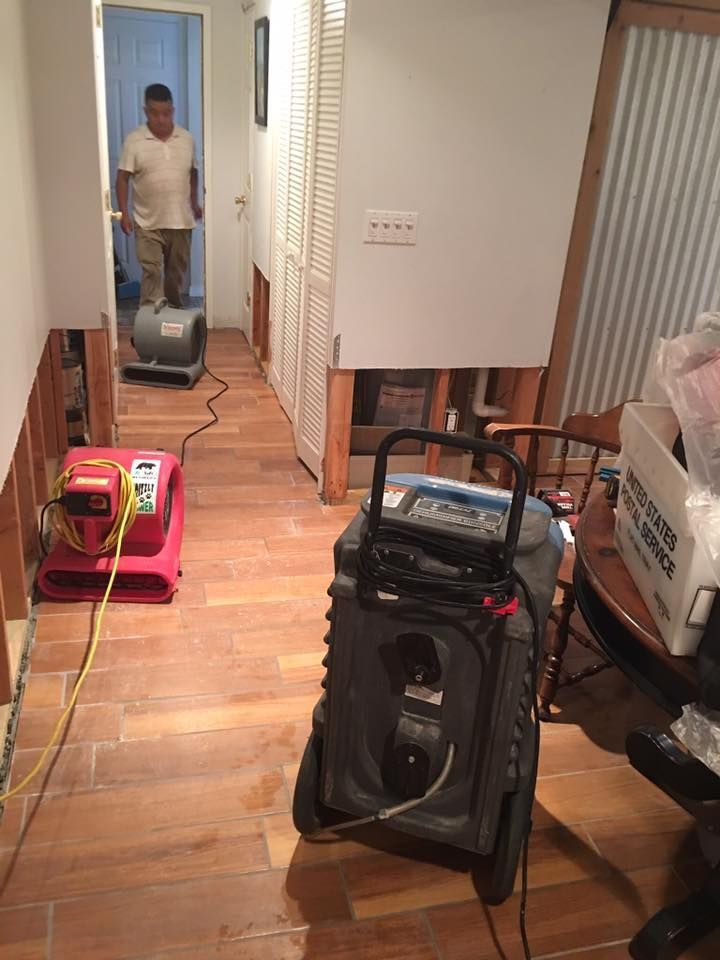 A man is standing in a hallway next to a vacuum cleaner.