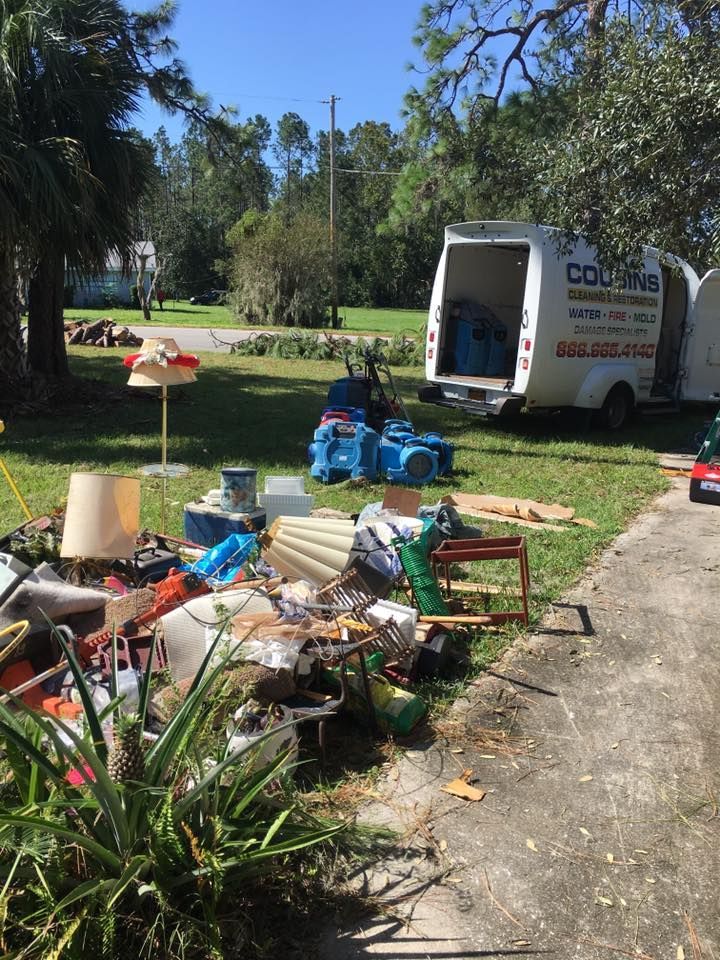 A white van is parked in the grass next to a pile of junk.