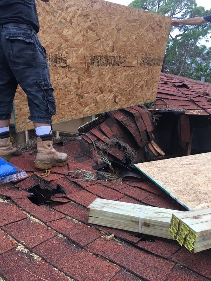 A man is standing on a roof with a piece of plywood on it.